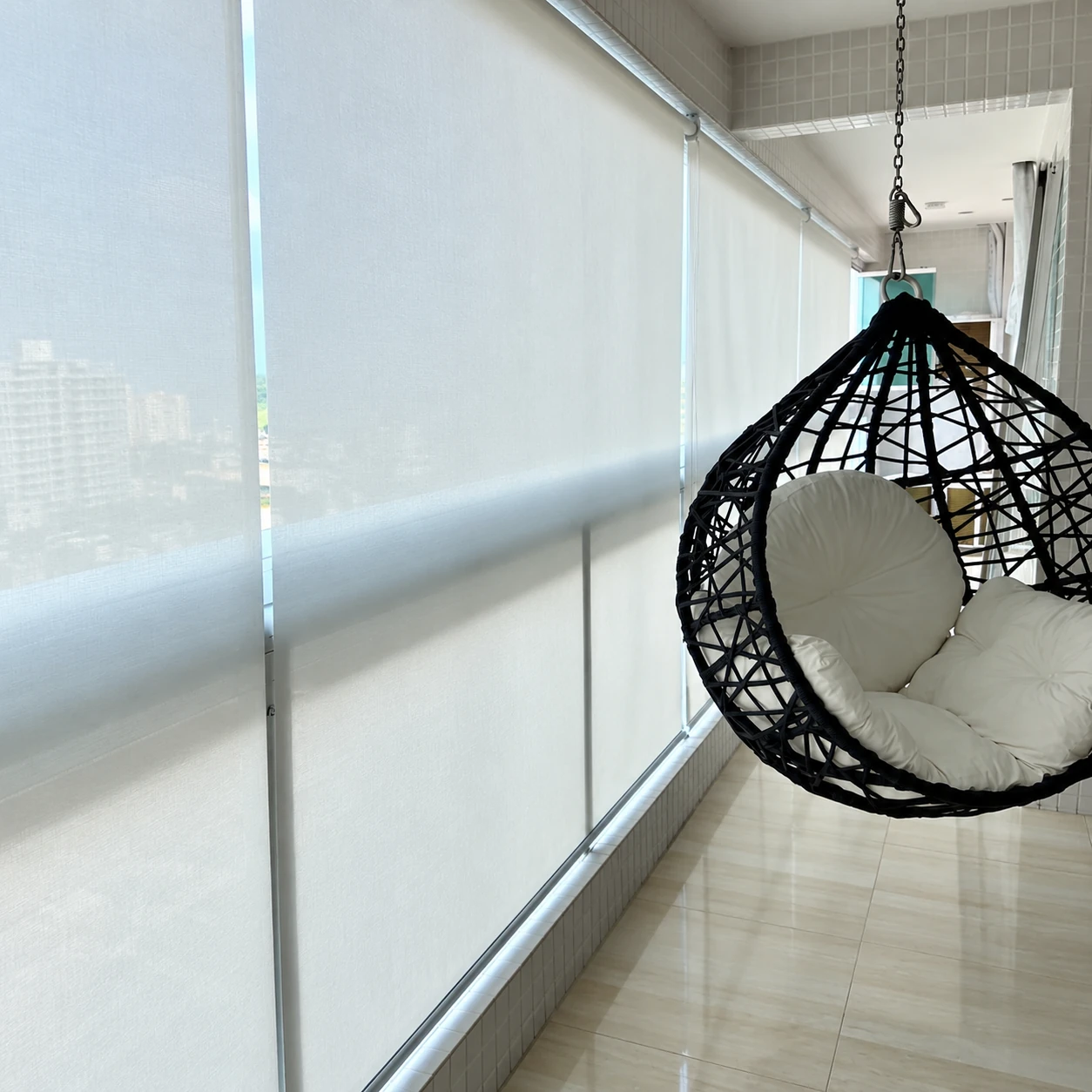 Persianas rolô screen em varanda com cadeira suspensa.